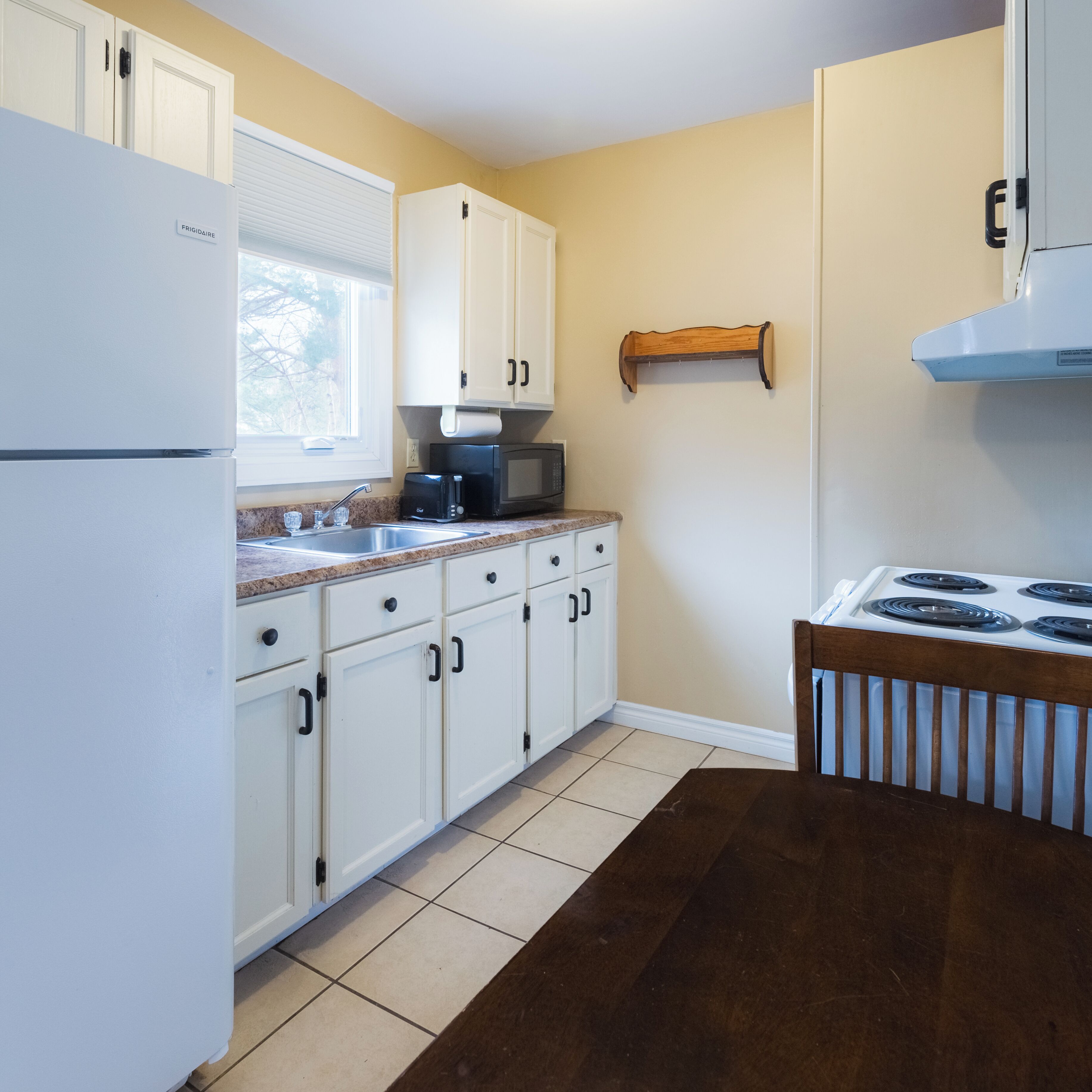 A kitchen with white cabinets, a stove, a microwave, and a refrigerator.