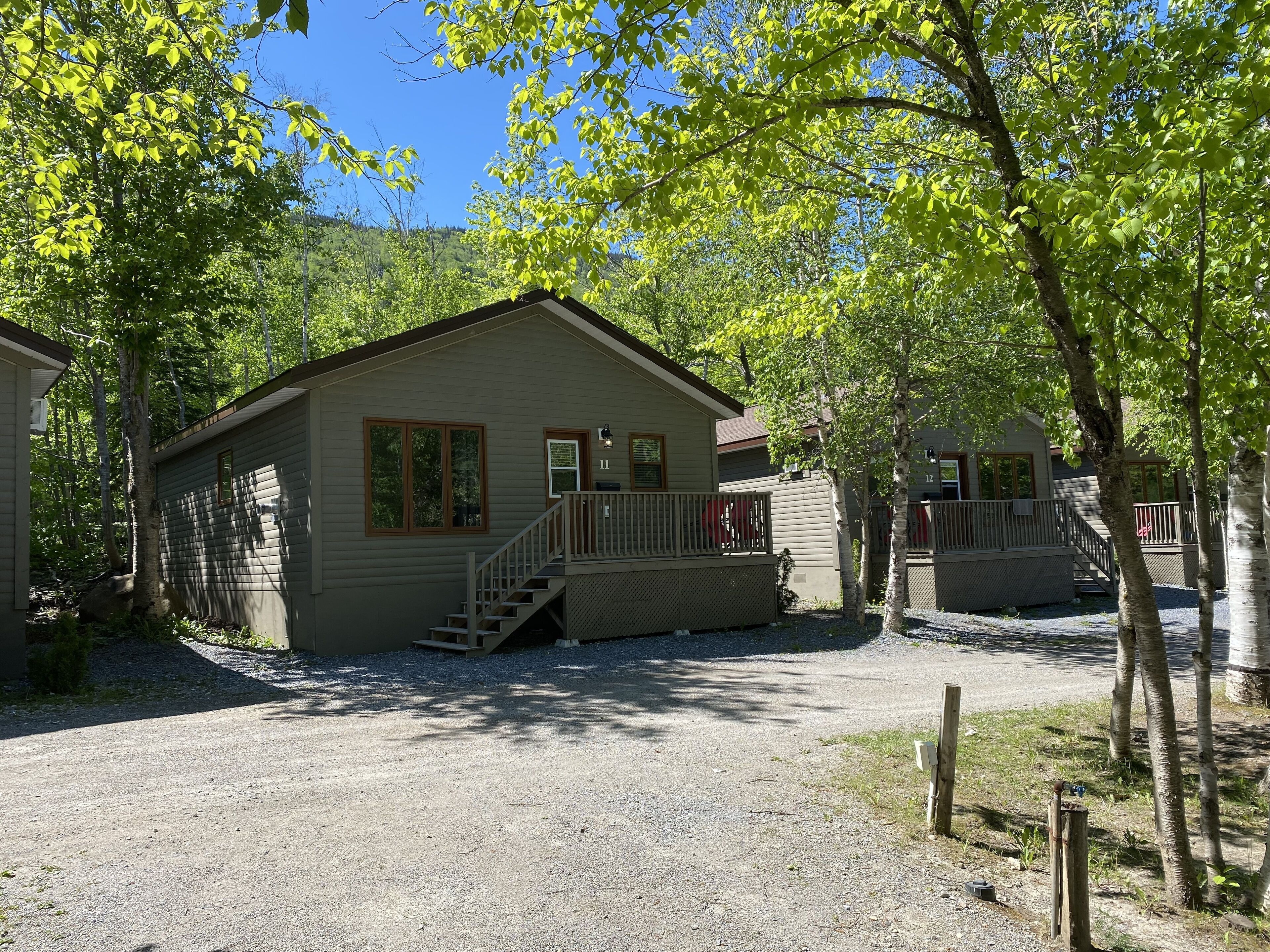 A small, single-story cabin with a front porch and a staircase leading to a deck.