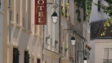 Ein Hotel mit einem auffälligen 'HOTEL'-Schild, klassischer Architektur und einem Radfahrer im Hintergrund.