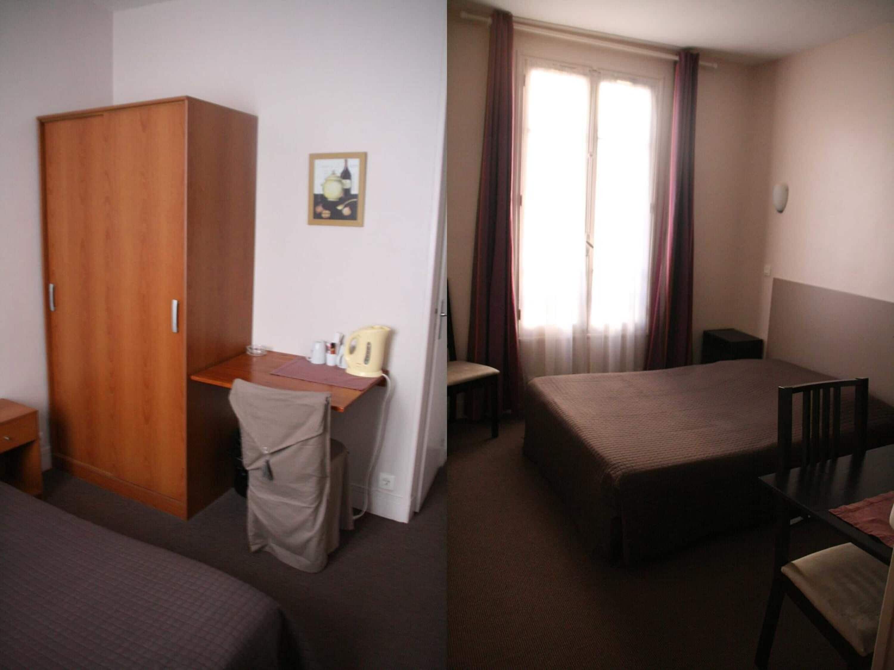 A hotel room with a wooden wardrobe, a desk with a chair, a bed, and a window with curtains.