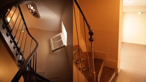A staircase with a wooden handrail and a light fixture on the wall. - Hôtel du Roussillon (Paris)