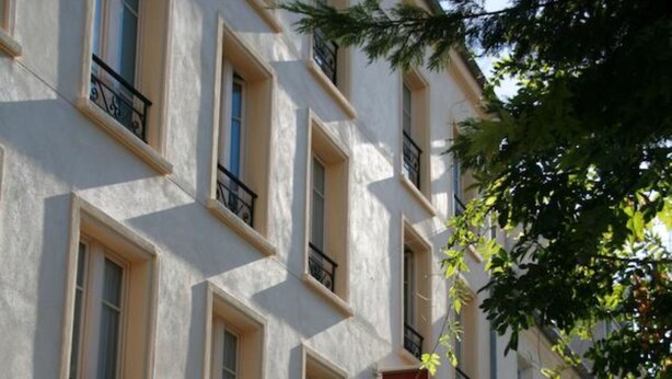 A hotel building with multiple windows and balconies, a sign indicating it is a hotel, and a cobblestone street in front. - Hôtel du Roussillon (Paris)