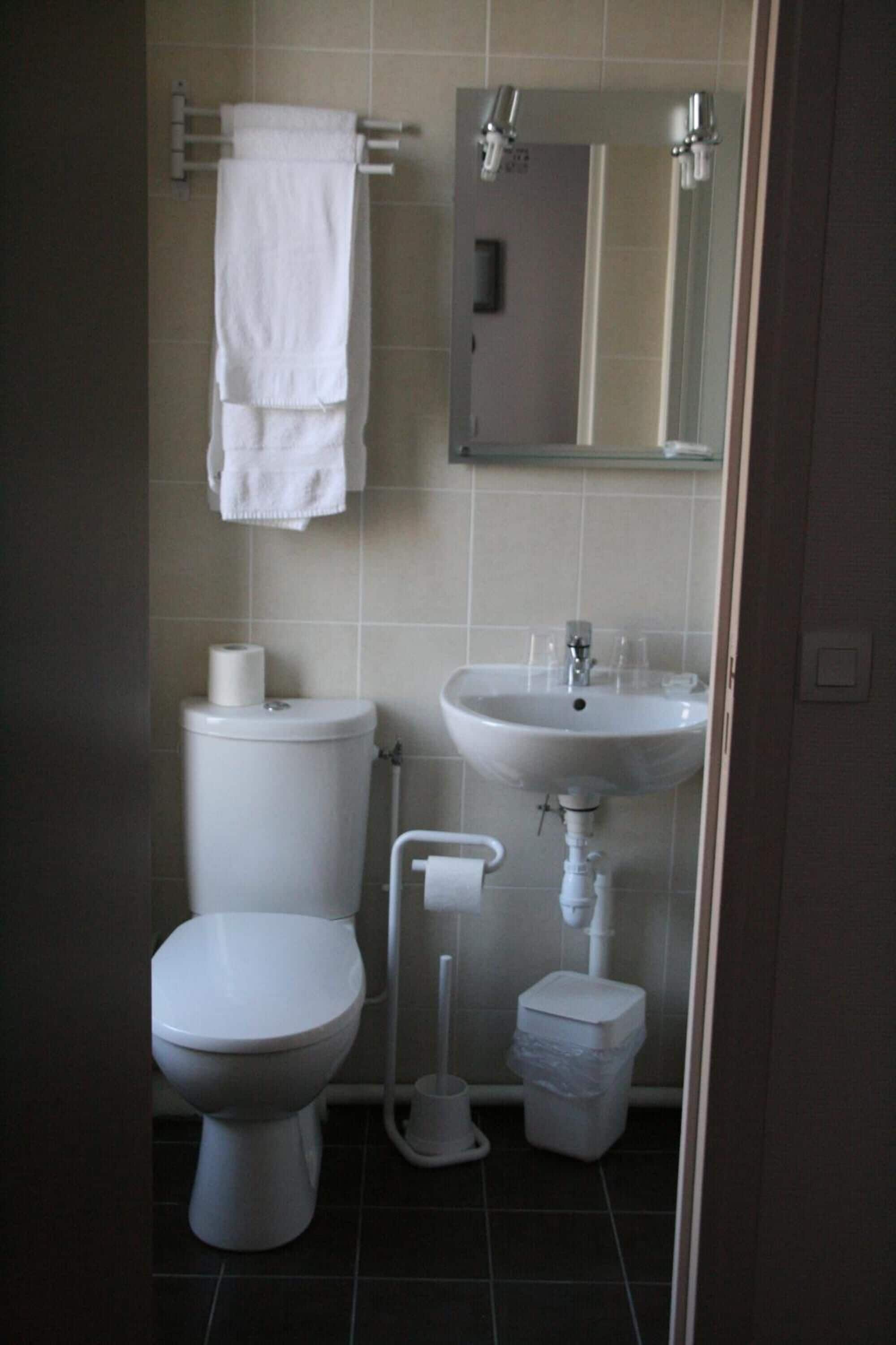 Une salle de bain équipée de toilettes, d’un lavabo et d’un porte-serviettes.