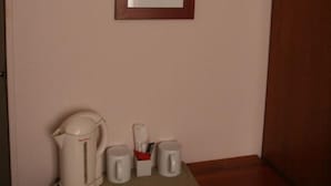 A small wooden bench with a kettle, two mugs, and a cup holder against a wall with a framed picture. - Hôtel du Roussillon (Paris)