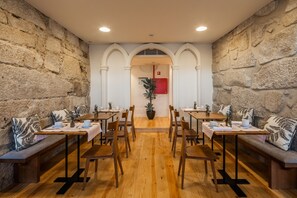 A dining area with wooden tables and benches, stone walls, and a central archway. - Porto River (Porto)