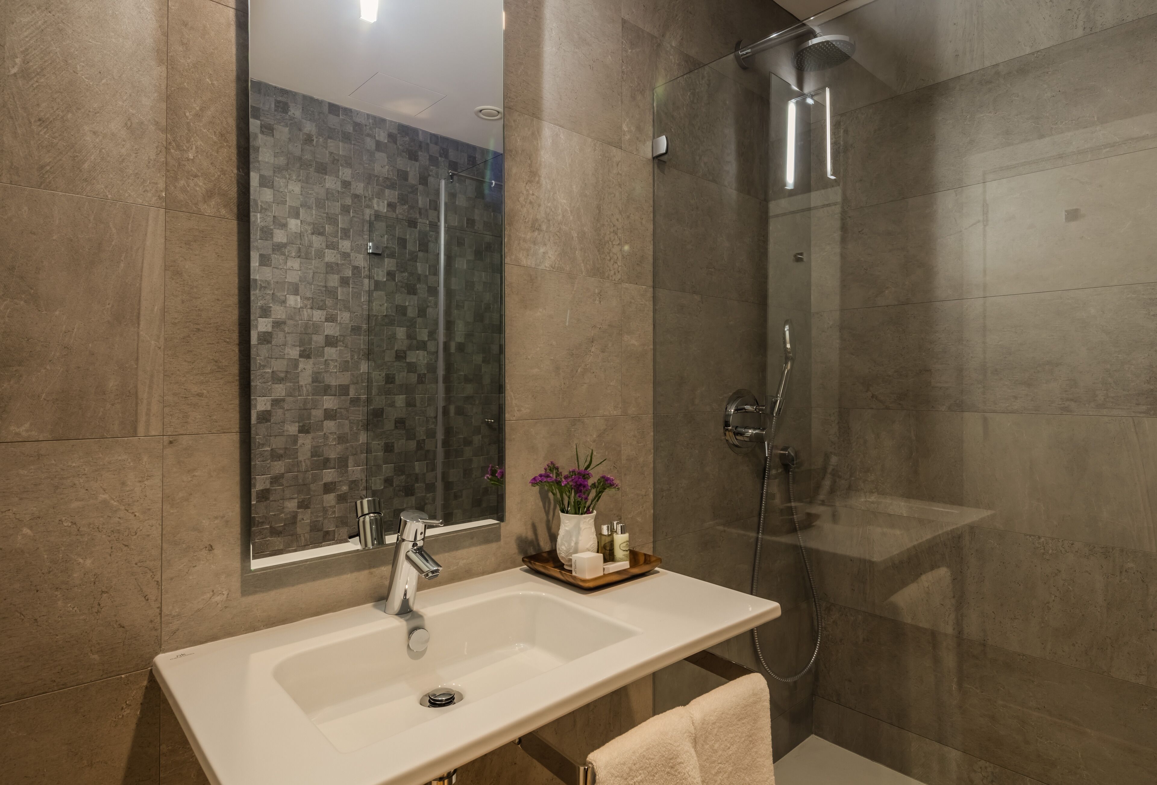 A modern bathroom with a large mirror, a sink, and a shower.