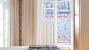 Une chambre avec un lit, une vue sur un pont rouge qui enjambe l’eau et, au loin, un paysage urbain.