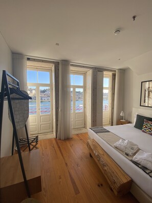 A hotel room with a large bed, wooden flooring, a view of the sea, and a balcony. - Porto River (Porto)
