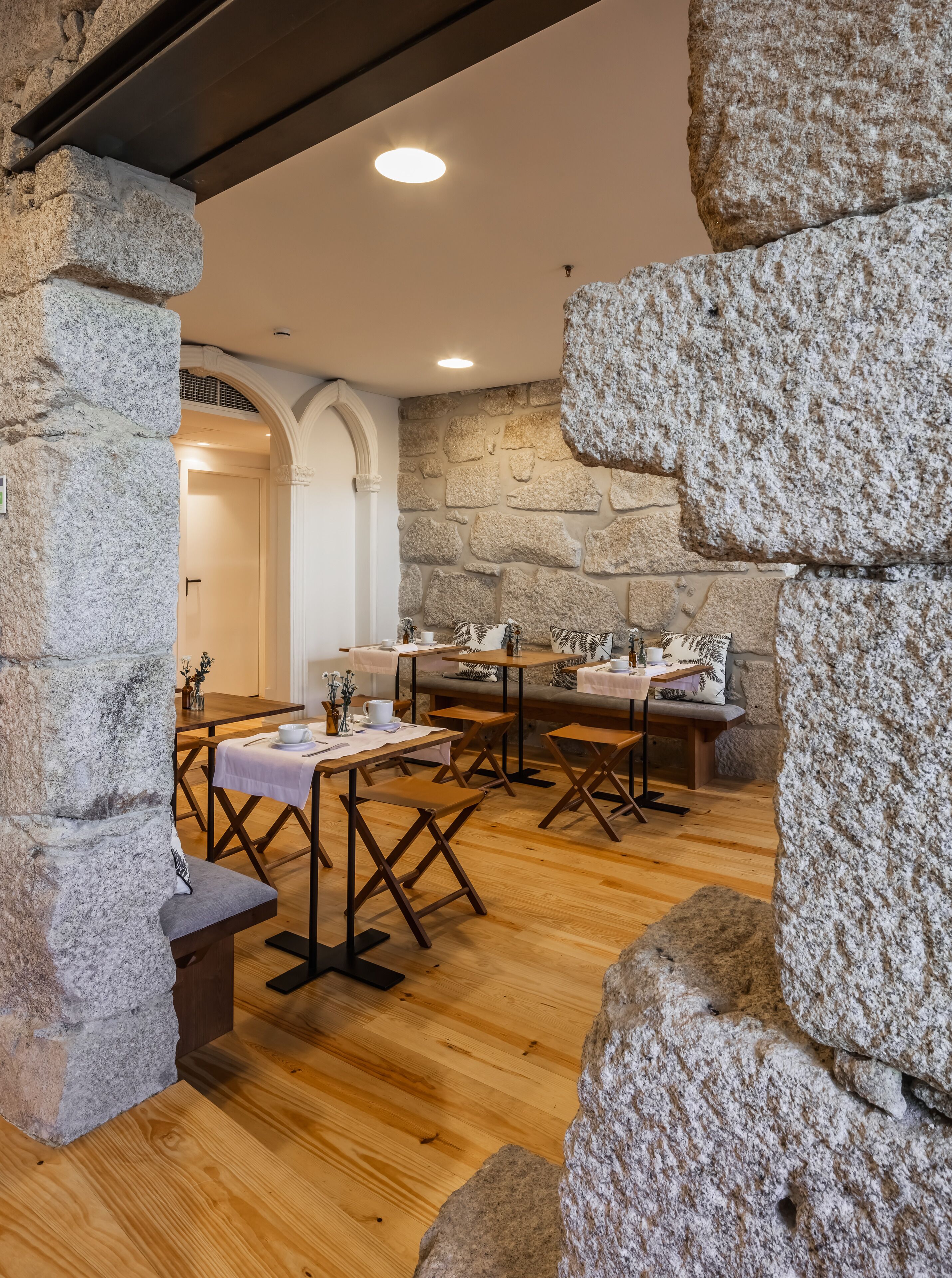 A cozy cafe with stone walls, wooden tables, and benches, featuring a warm, inviting atmosphere.