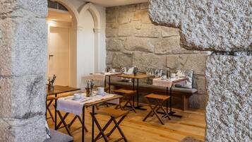 A cozy cafe with stone walls, wooden tables, and benches, featuring a warm, inviting atmosphere.