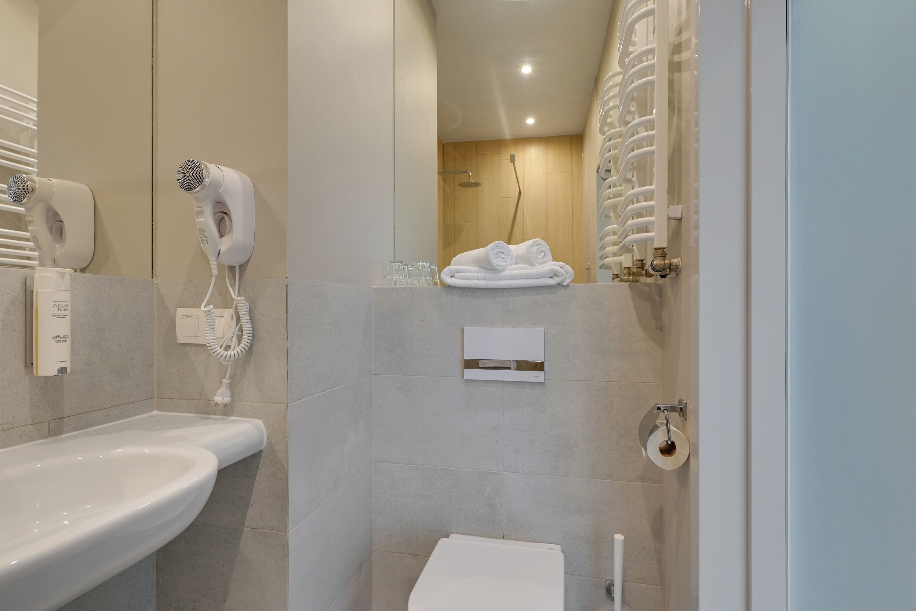 Casa de banho moderna com lavatório, secador de cabelo, porta-toalhas e sanita.