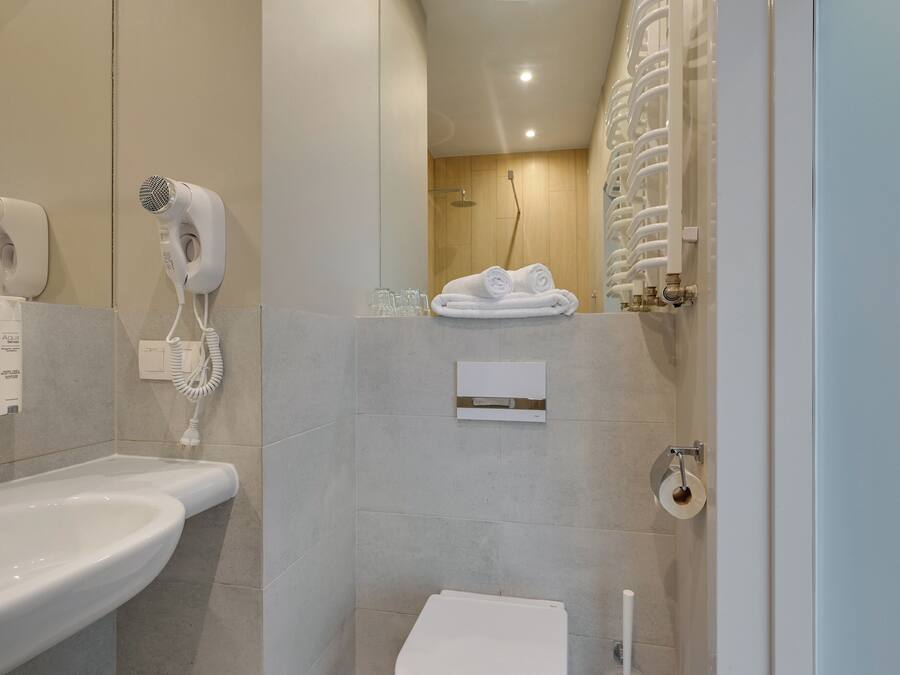 Casa de banho moderna com lavatório, secador de cabelo, porta-toalhas e sanita.