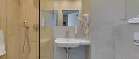 Une salle de bain moderne avec une douche à parois de verre, un lavabo blanc et une douchette à main.