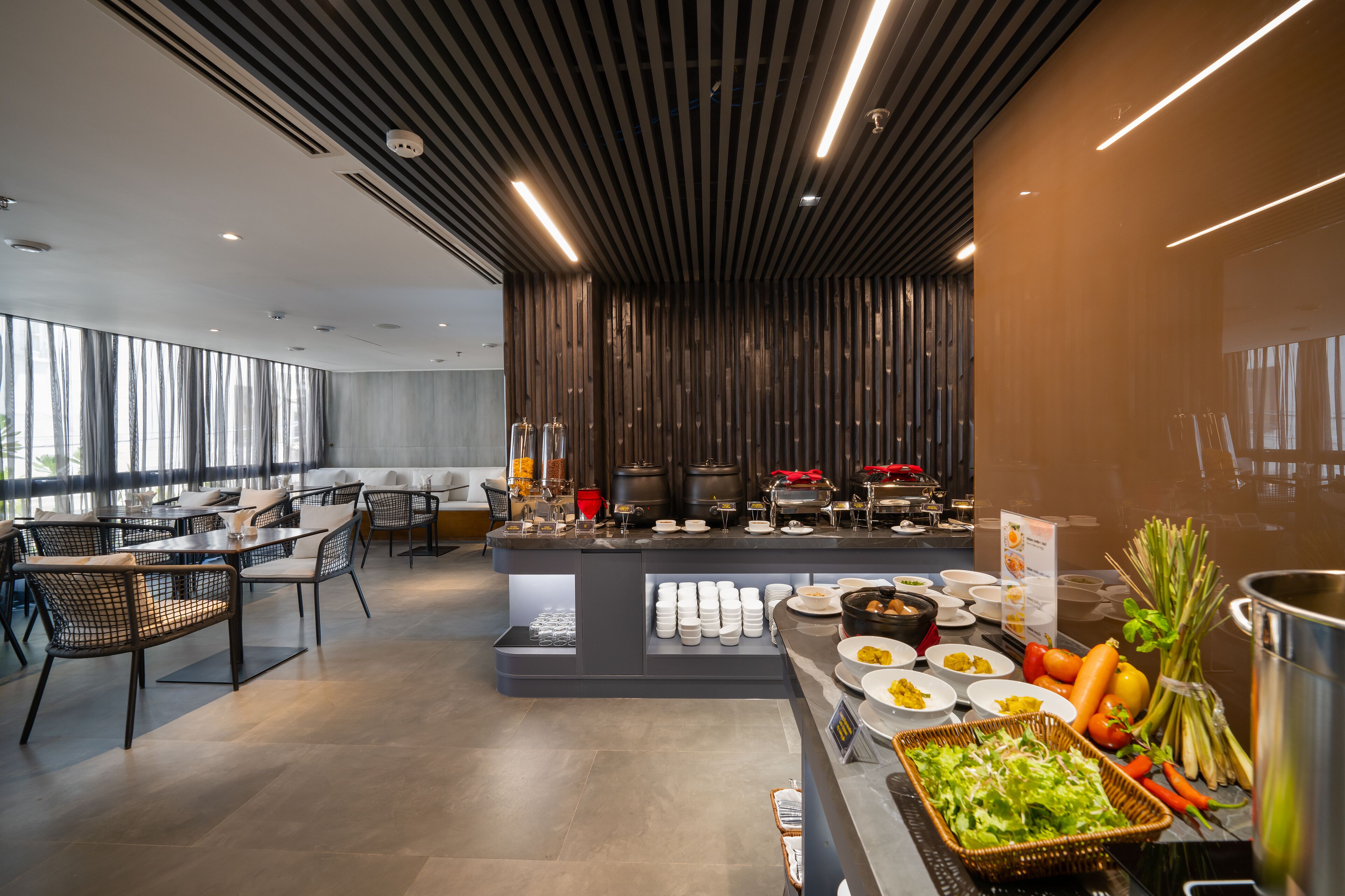 A modern dining area with a buffet setup, including various food items and a seating arrangement with chairs and tables.