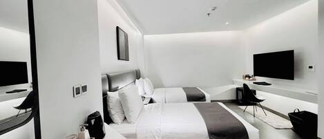 Een moderne hotelkamer met twee bedden, een flatscreen televisie, een bureau met stoel en een grote spiegel.
