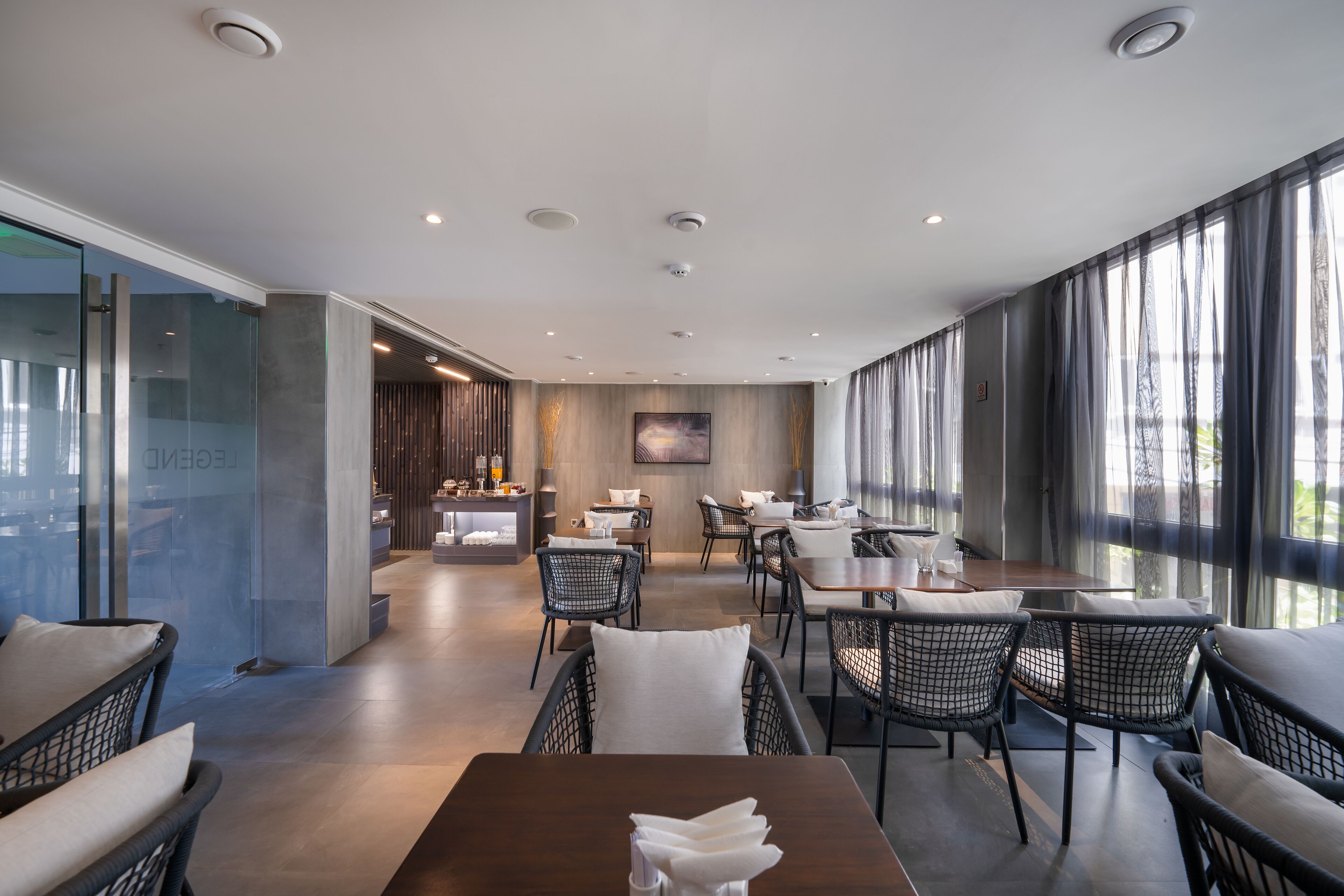 A modern dining area with glass partitions, wooden furniture, and a view of the outdoors.