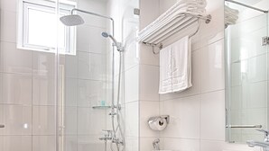 A modern bathroom with a glass-enclosed shower, a white toilet, a sink with a marble countertop, and a large mirror. - Sea Castle Hotel (Da Nang)
