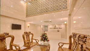 A luxurious lobby with ornate wooden furniture, a reception desk, and a decorative wall panel. - Sea Castle Hotel (Da Nang)
