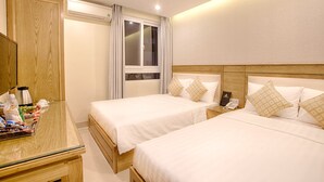 A hotel room with two beds, a wooden wardrobe, a bedside table with a lamp, and a window with curtains. - Sea Castle Hotel (Da Nang)