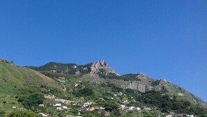 Un paysage montagneux caractérisé par un sommet rocheux imposant et quelques maisons éparpillées au pied de la montagne.