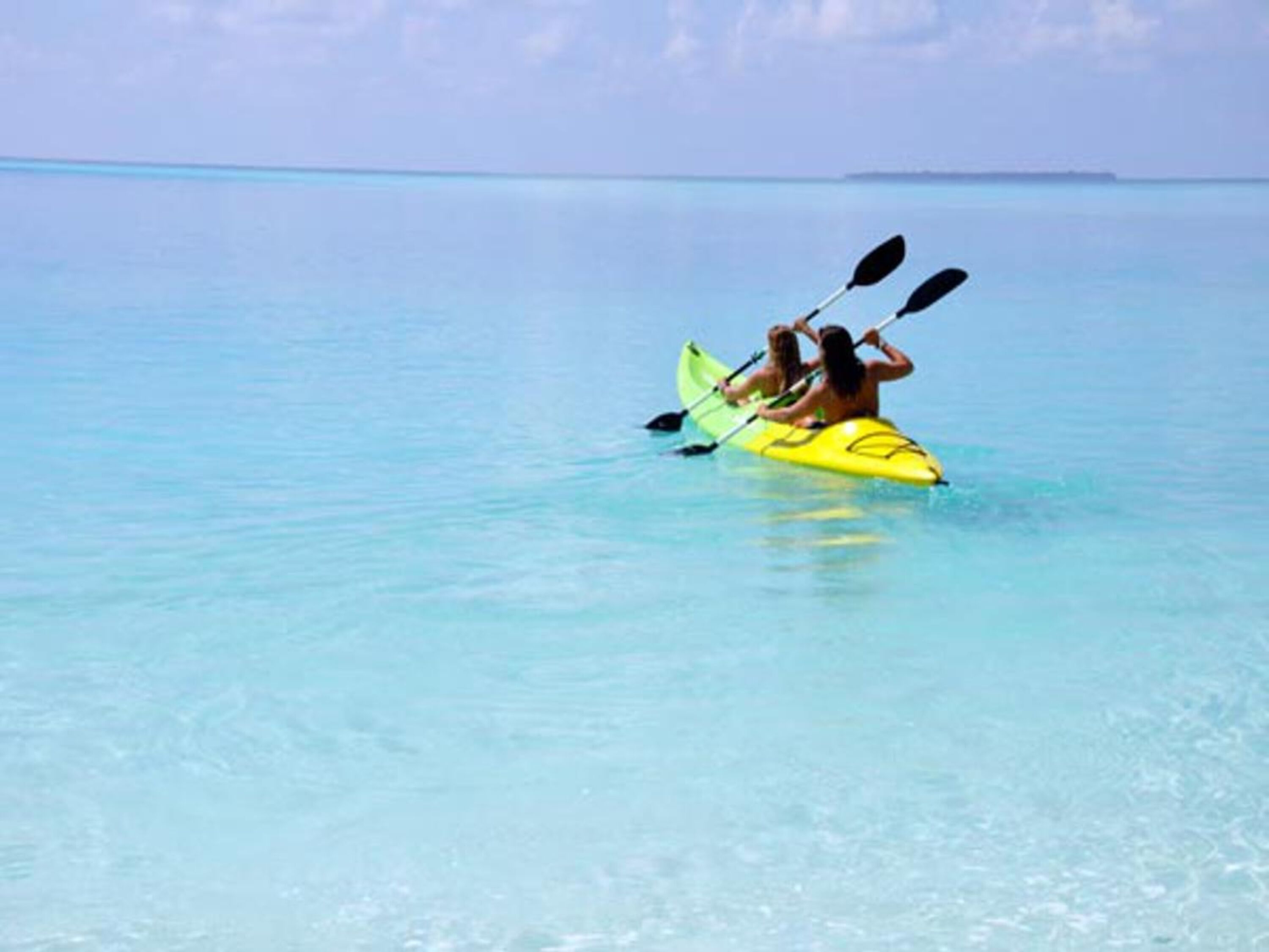 A person kayaking on a clear blue sea.
