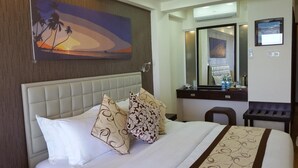 Une chambre d’hôtel avec un grand lit, une tête de lit, une table de chevet, un miroir et un tableau au mur.