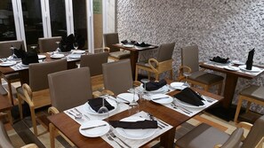 Een restaurant met meerdere tafels voor diners, met een modern interieur, houten meubels en een patroonwand.