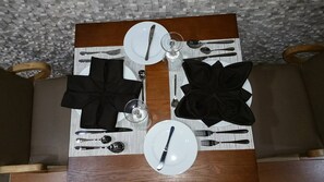 Una mesa de comedor dispuesta con platos, cubiertos y servilletas.