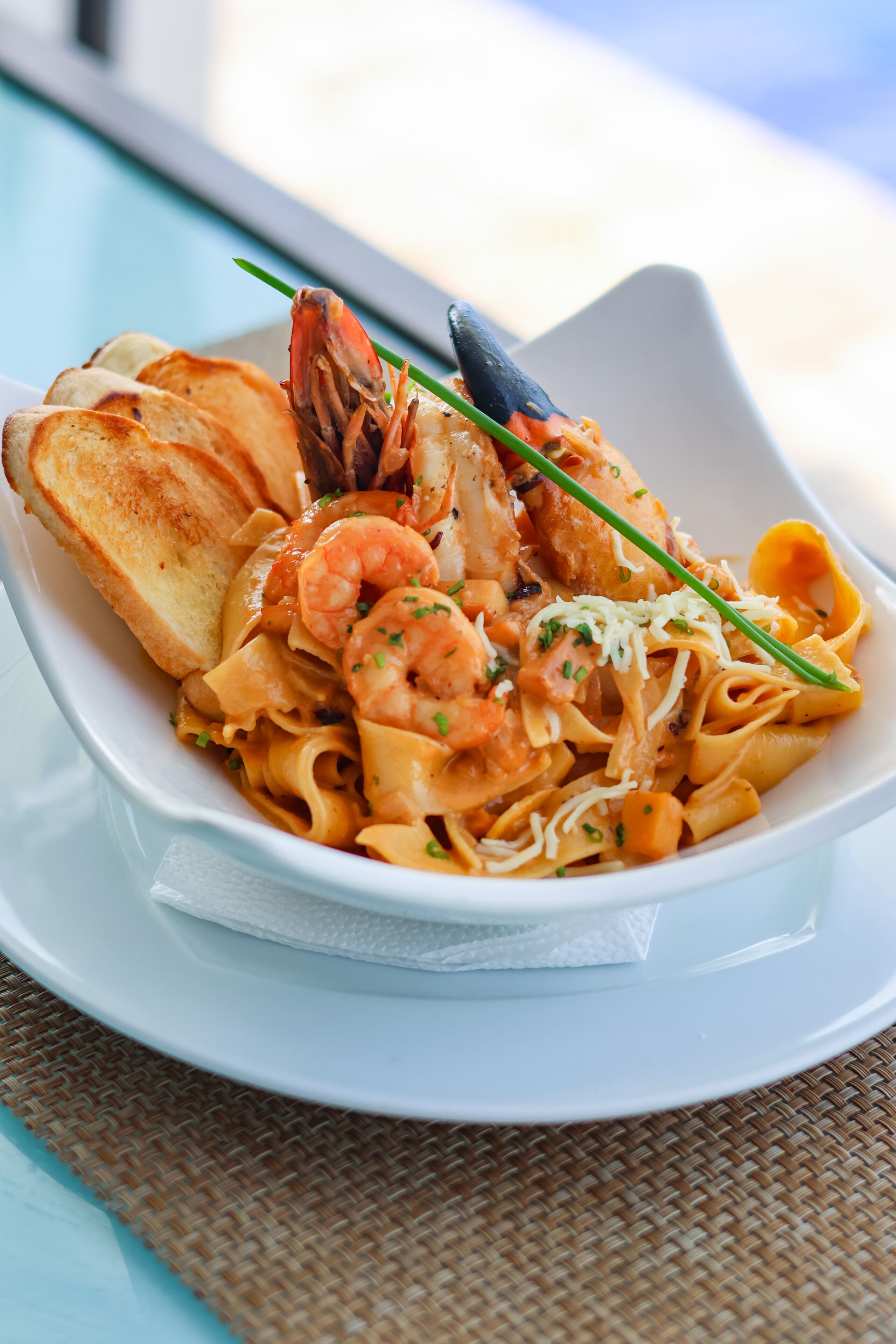 A seafood pasta dish with shrimp, mussels, and bread on a white plate.