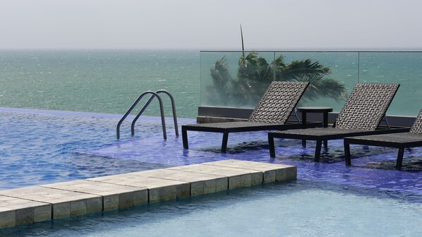 A pool with lounge chairs and a glass barrier. - Hotel Poseidon (Manta)