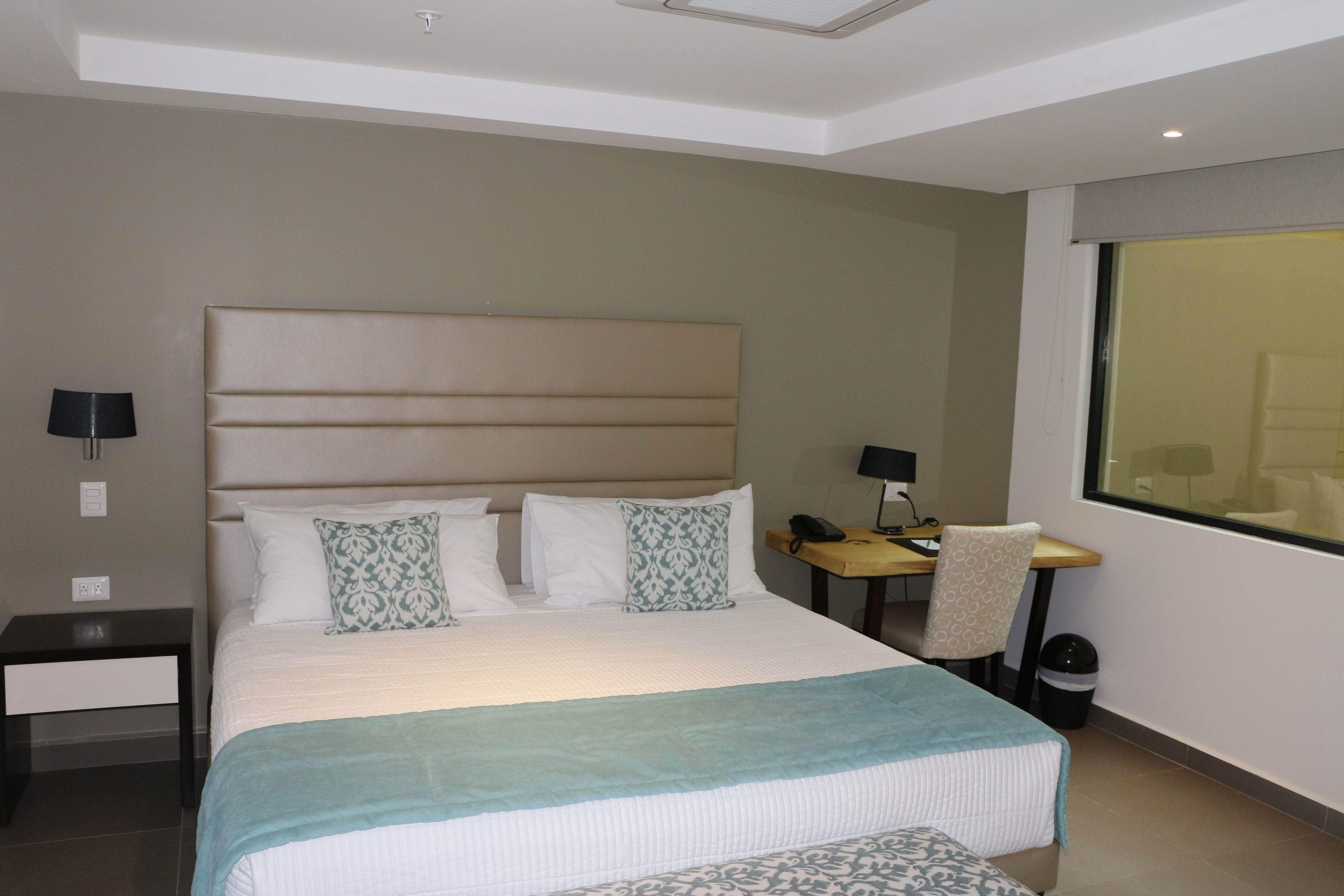 Una habitación de hotel con una cama grande, un escritorio, una silla y una ventana.