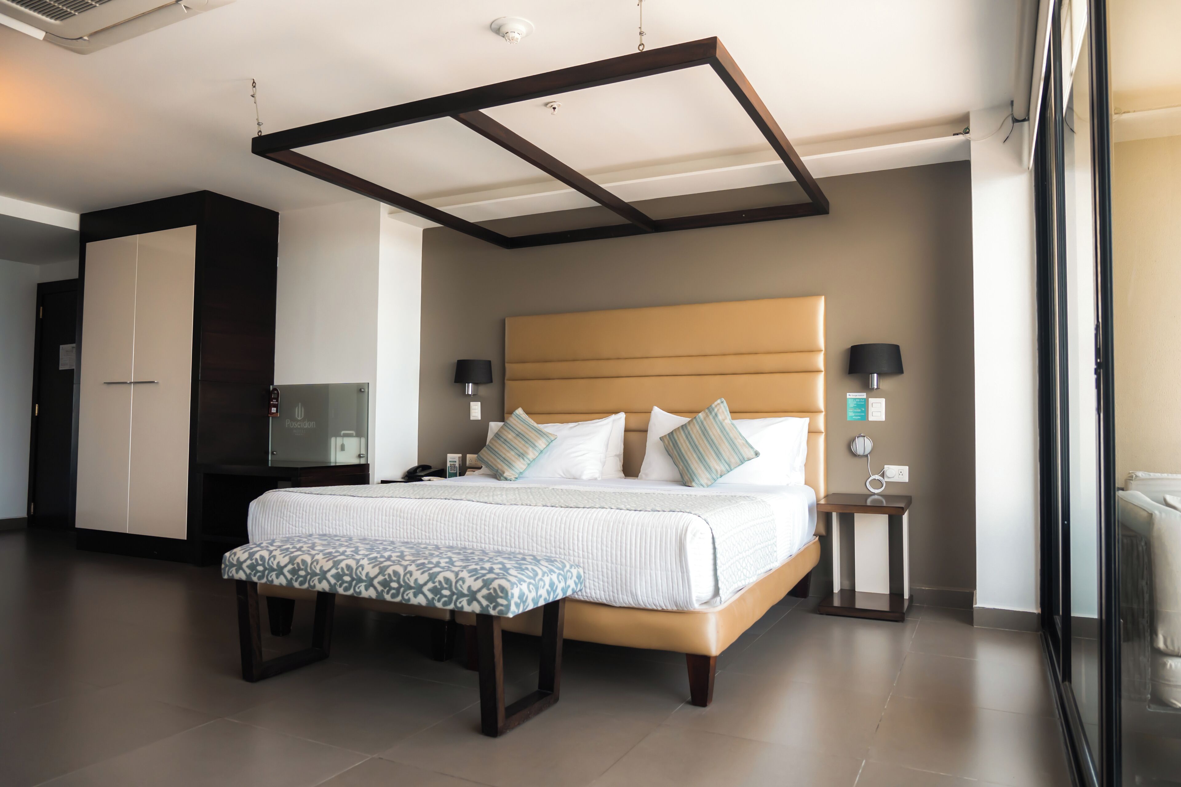 A modern hotel room with a large bed, bedside tables, a wardrobe, and a television.