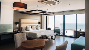 Une chambre d’hôtel moderne avec un grand lit, un bureau et une vue sur la mer.