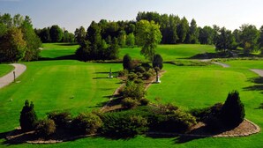 En golfbana med välskött gräs, träd och en klar himmel.