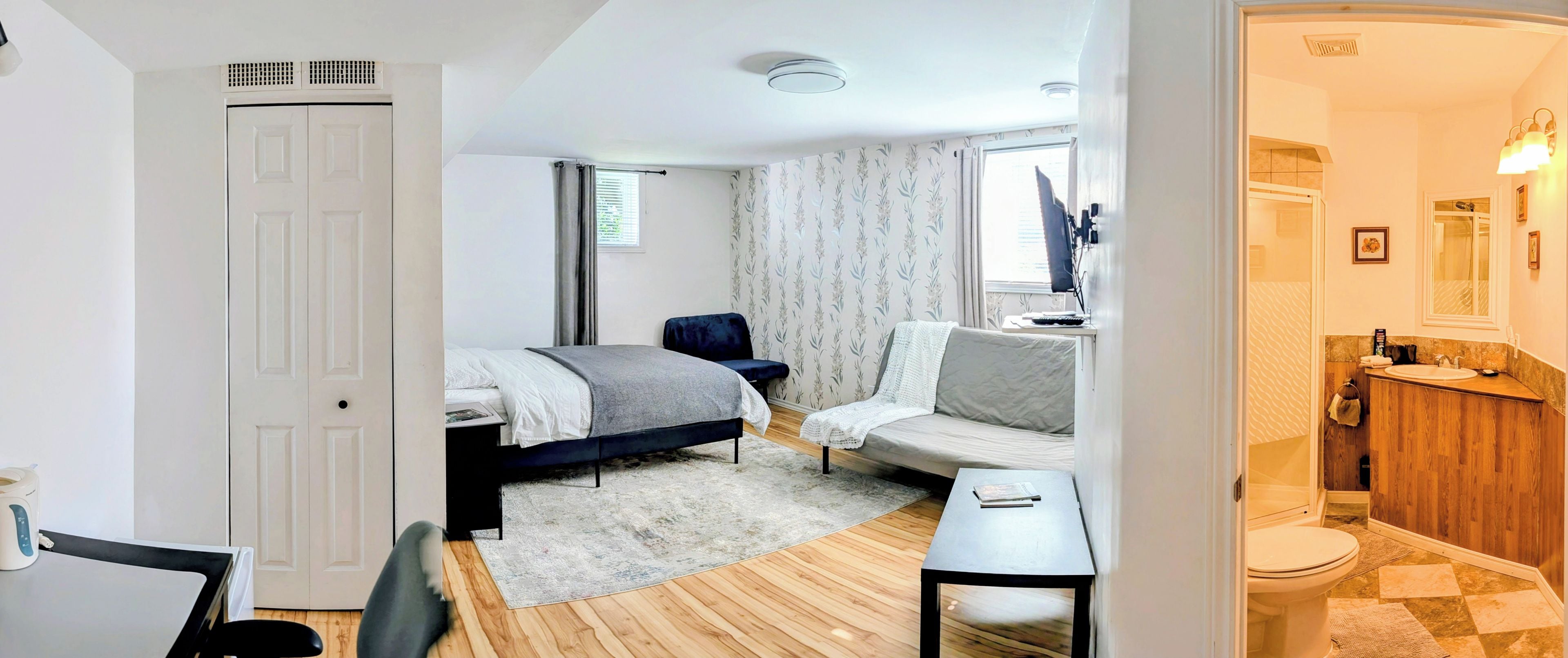 Ein Hotelzimmer mit Bett, einer Couch, einem kleinen Tisch und einem Badezimmer mit Waschbecken und Toilette.