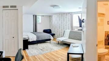 Ein Hotelzimmer mit Bett, einer Couch, einem kleinen Tisch und einem Badezimmer mit Waschbecken und Toilette.