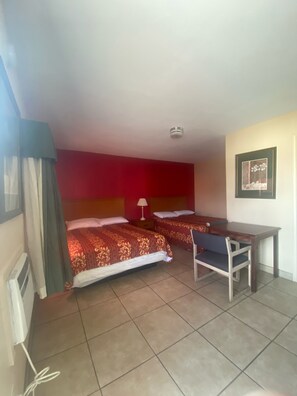 Une chambre d’hôtel avec deux lits, un bureau et une chaise.