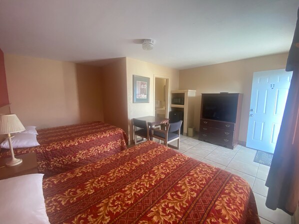 A hotel room with two beds, a desk, a chair, a television, and a door with the number 11.