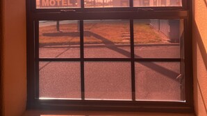A motel sign through a window with a grid pattern. - Sunset Motel (Alice)