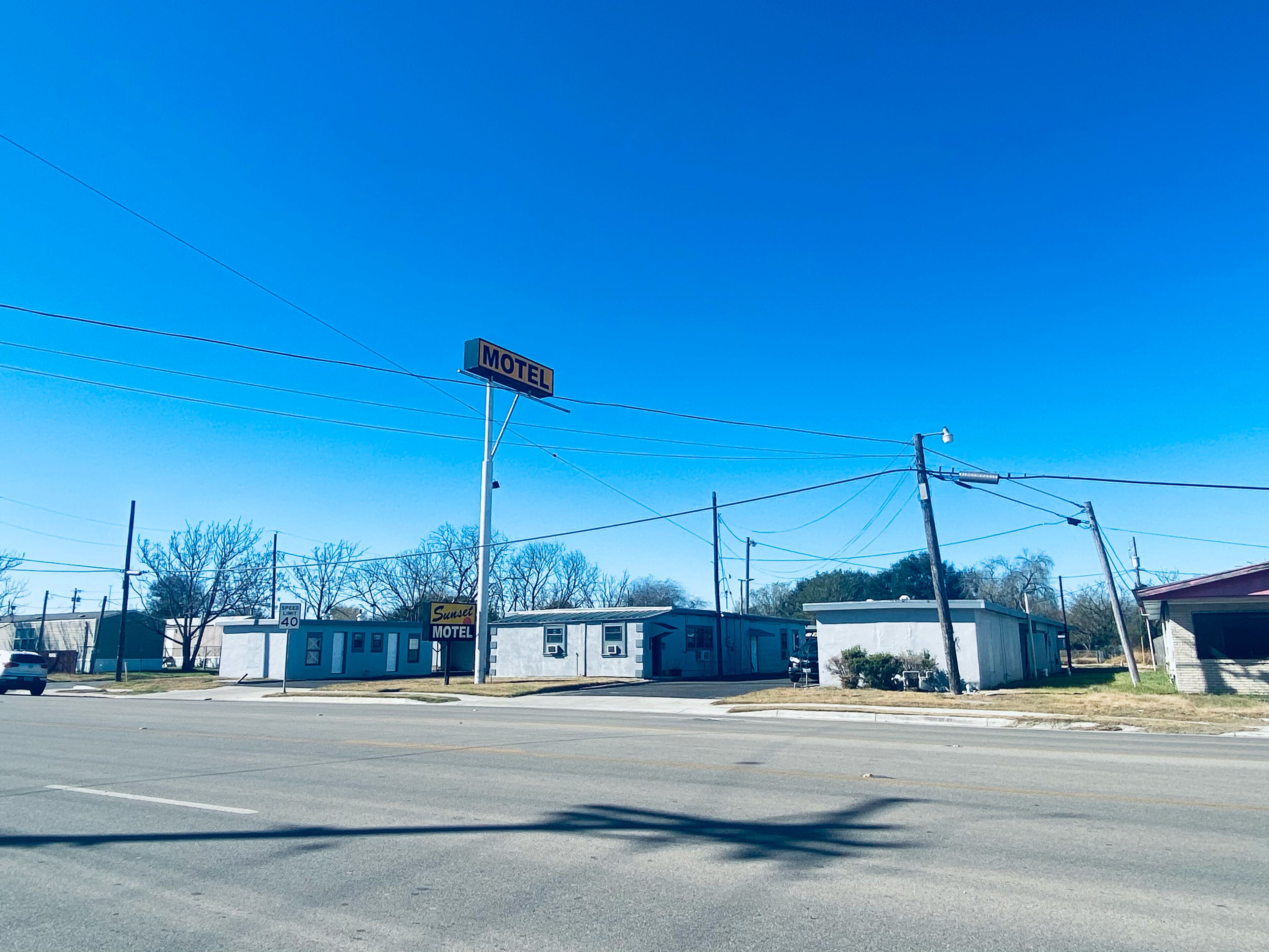A motel with a 'Motel' sign, a speed limit sign of 40, and a 'Sunrise Motel' sign.