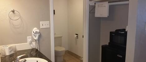 A bathroom with a white sink, a hairdryer, a toilet, and a black coffee machine.