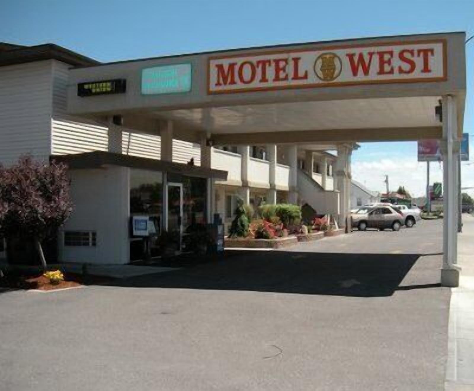 Un motel llamado 'Motel West' con una estación de servicio, entrada tipo parabrisa y un coche estacionado afuera.