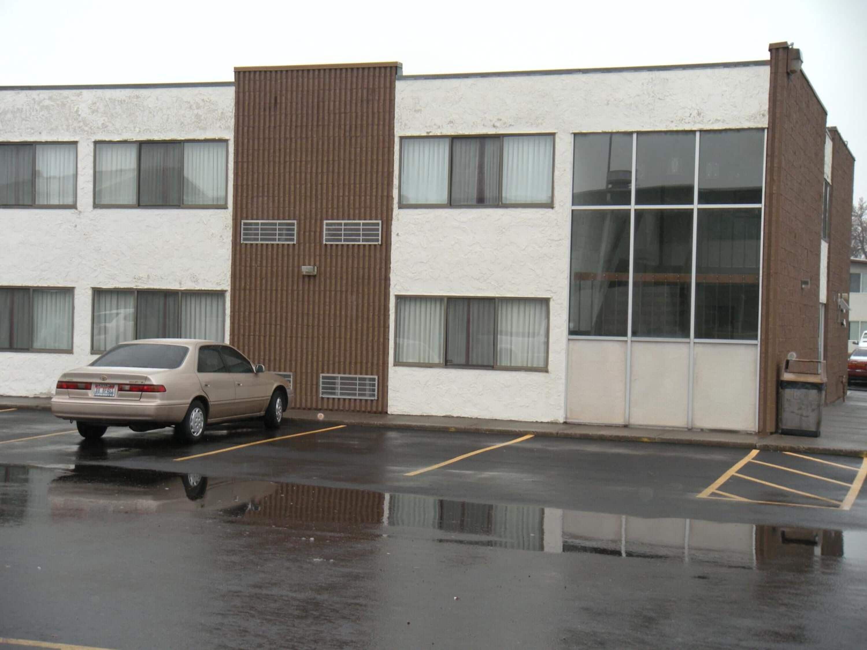 Un immeuble de deux étages avec un parking situé devant.
