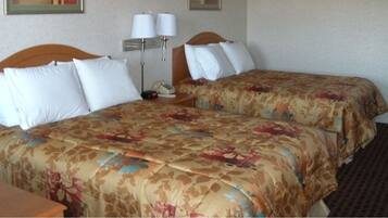 Habitación de hotel con dos camas, cada una con ropa de cama floral, una mesita de noche con lámpara y teléfono.