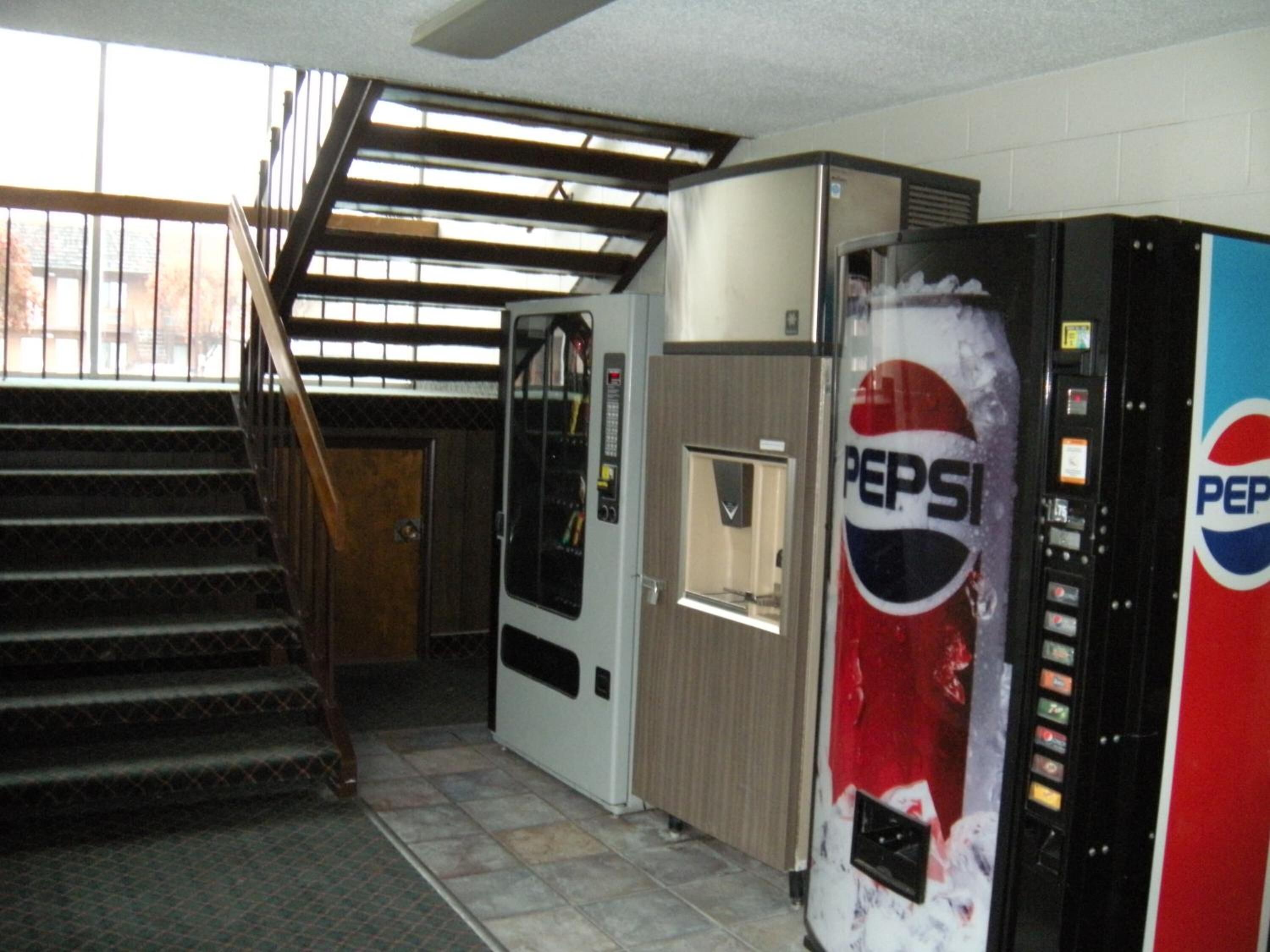 A stairway leading to a room with a vending machine and a door.