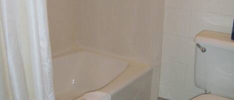 Un baño con bañera, inodoro y un perchero para toallas.