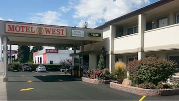 Welcome to Motel West, a two-story building with a flat facade and a balcony on the upper floor, offering easy access to parking and nearby amenities.