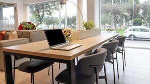 A modern interior with a wooden table, a laptop, and bar-style seating. - Palmetto Hotel Business San Miguel (Lima)