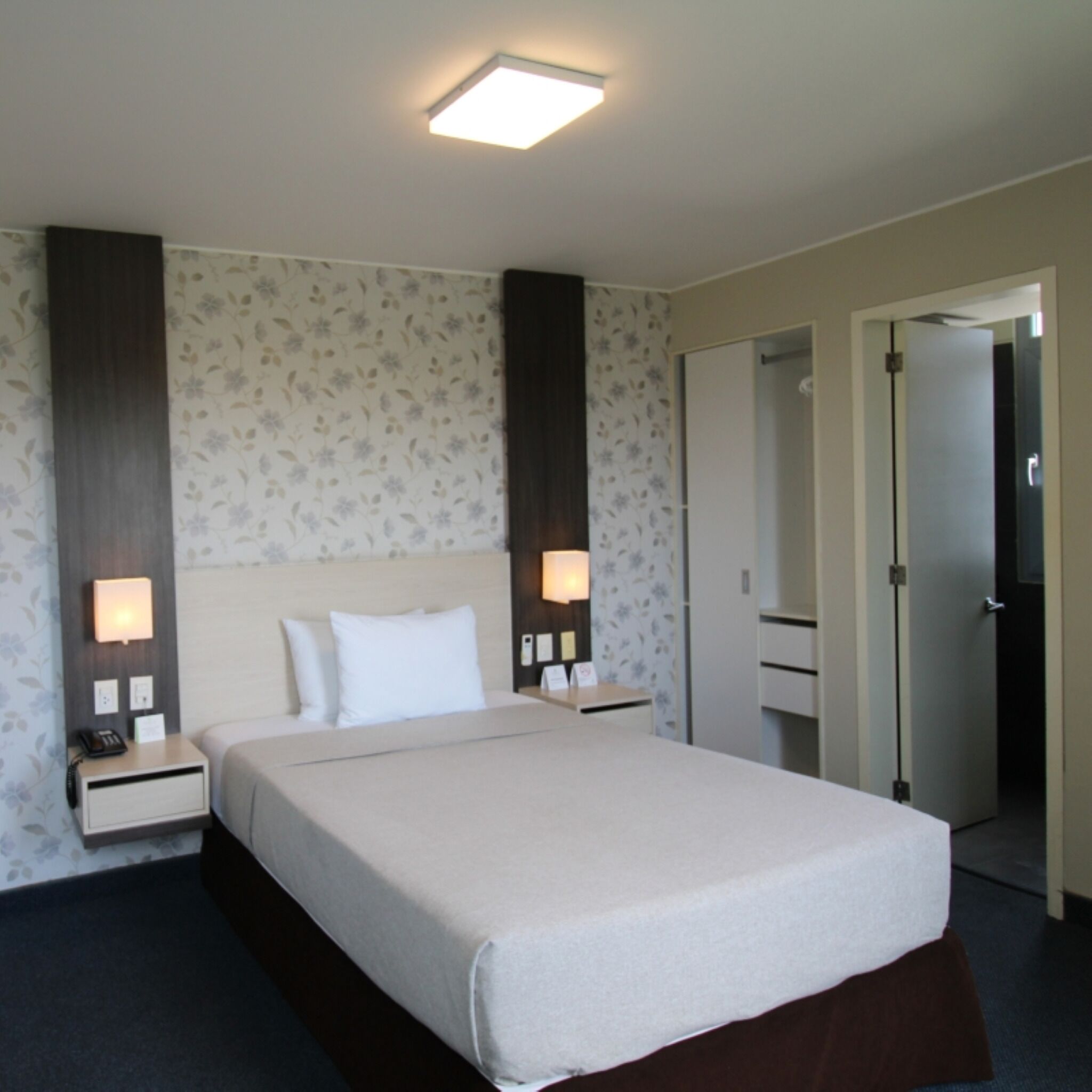 A hotel room with a bed, nightstands, a mirror, and a door.