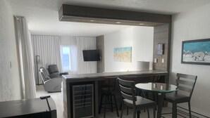 Una cocina moderna con una isla central, asientos tipo barra y un comedor con sillas.